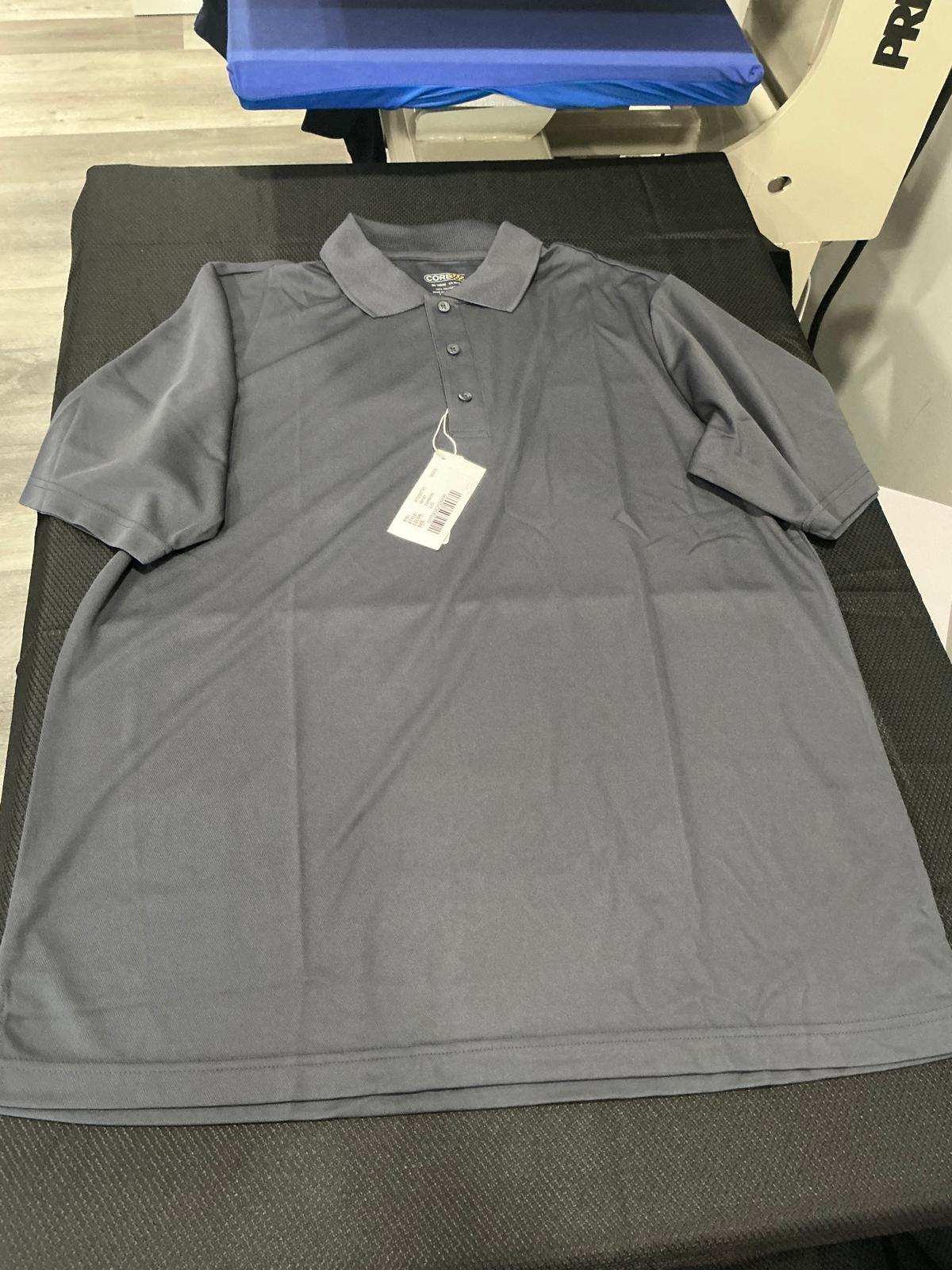 A plain carbon gray short-sleeve piqué polo with a collar and a three-button placket, laid flat and unprinted with its tag still attached on the black pad of the heat press